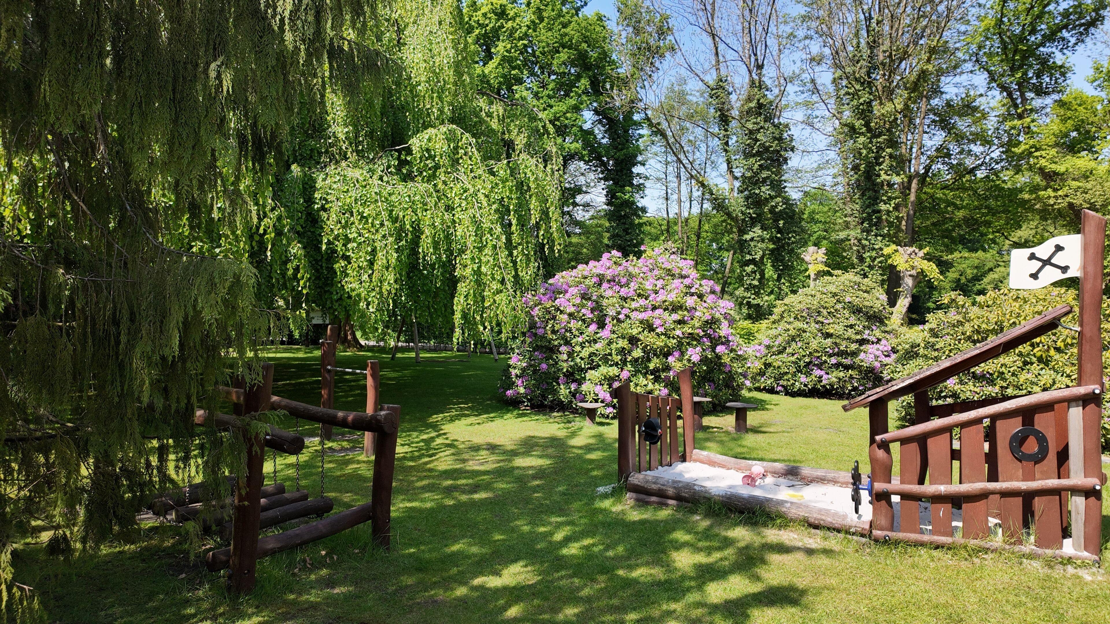 A wooden swing set, a small bridge, and a flag with a black cross.