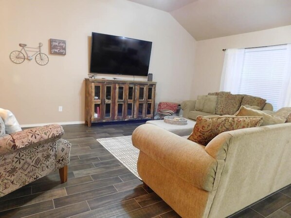 A living room with a sofa, a patterned armchair, a television, and a cabinet.