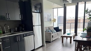 Eine moderne Küche mit Edelstahlgeräten, ein Essbereich mit Tisch und Stühlen sowie ein großes Fenster mit Blick auf die Stadt.