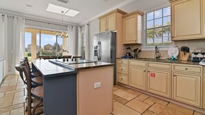 A modern kitchen with a central island, beige cabinetry, and a large window providing natural light. - Best Golf Course View, 6 mi from Disney! (Reunion)