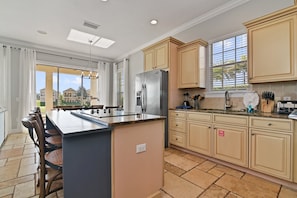 A modern kitchen with a central island, beige cabinetry, and a large window providing natural light. - Best Golf Course View, 6 mi from Disney! (Reunion)