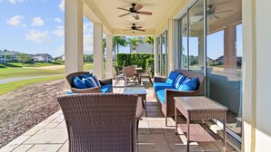 A covered outdoor area with wicker furniture, ceiling fans, and a view of a golf course. - Best Golf Course View, 6 mi from Disney! (Reunion)