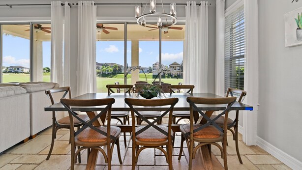 A dining area with a table and chairs, a chandelier, and a view of a golf course. - Best Golf Course View, 6 mi from Disney! (Reunion)