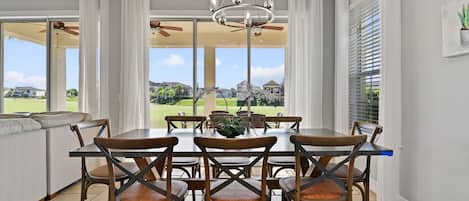 Un espace repas comprenant une table et des chaises, de grandes fenêtres et une vue sur un terrain de golf.