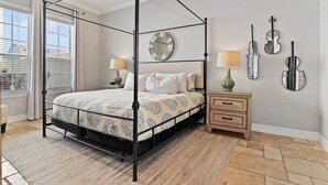 A four-poster canopy bed with a patterned bedspread, two bedside lamps, a wooden nightstand, and wall-mounted violin-shaped mirrors. - Best Golf Course View, 6 mi from Disney! (Reunion)