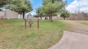 A sign for a property named "FRAME" with a grassy area, trees, and a building in the background.