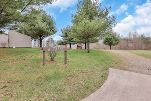 A sign for a property named "FRAME" with a grassy area, trees, and a building in the background.