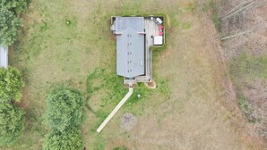 An aerial view of a building with a flat roof, a covered patio area with outdoor seating, and a visible pathway leading to the entrance.