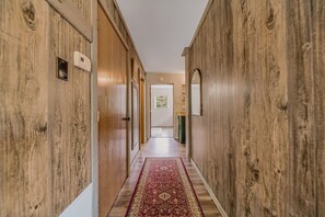 A hallway with wooden walls, a patterned carpet, and a door at the end. - Red Roost A-Frame - New Hot Tub (Rockbridge)