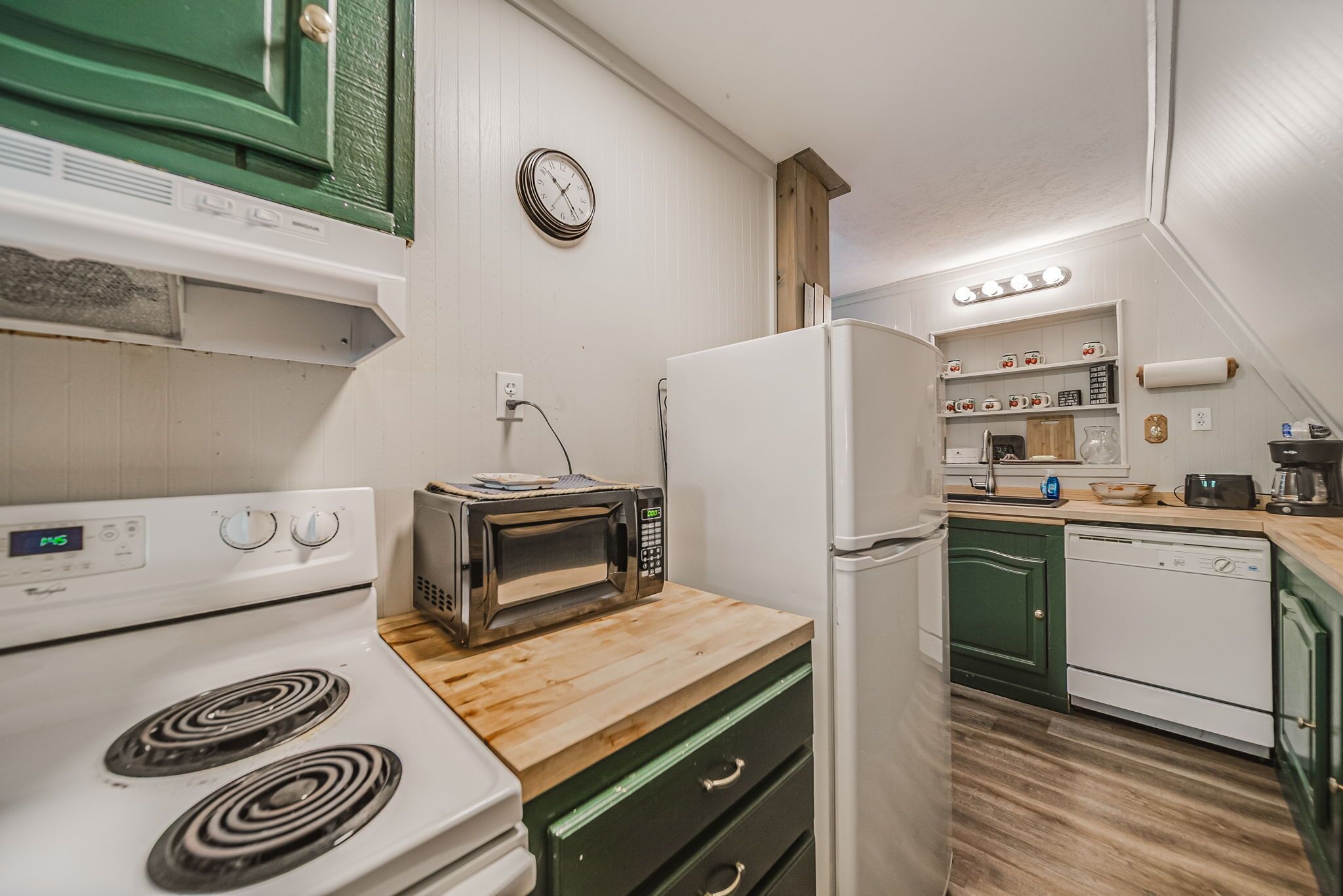 Una cocina funcional con estufa, tostadora, refrigerador y encimera de madera.