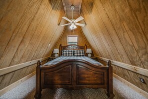 A wooden-framed attic bedroom with a bed, two bedside lamps, and a ceiling fan. - Red Roost A-Frame - New Hot Tub (Rockbridge)