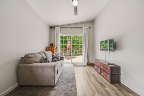 A modern living room with a sofa, a TV, and a wooden cabinet. - Red Roost A-Frame - New Hot Tub (Rockbridge)