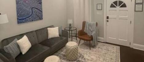 A living room with a dark grey sofa, a round coffee table, a patterned rug, and a ceiling fan.
