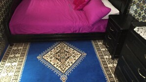 A bed with a purple bedspread and pillows, a black headboard, and a patterned blue and white floor. - House (Marrakech)