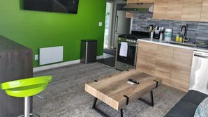 A modern kitchen with green walls, a wooden dining table, and a built-in oven. - Urban Oasis to Love, Near SF, Free Parking Onsite (Hayward)