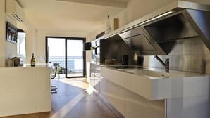 Een moderne keuken met een groot kookeiland, roestvrijstalen apparatuur en uitzicht naar buiten.
