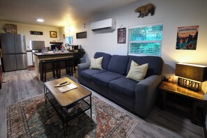 Ein gemütliches Wohnzimmer mit Sofa, Couchtisch und einer Küche im Hintergrund.