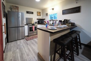 Eine moderne Küche mit Edelstahlgeräten, einer Holztheke mit Barhocker und Blick ins Freie.