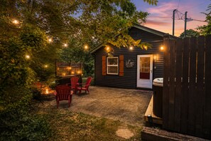 Eine Holzhütte mit überdachter Veranda, roten Adirondack-Stühlen und Lichterketten.