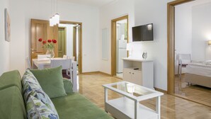 Una sala de estar moderna con un sofá verde, una mesa de centro de vidrio y un comedor con una mesa y sillas blancas.