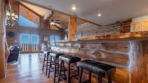 A log cabin interior with a bar area, wooden floors, and a staircase leading to an upper level. - Secluded Cabin Retreat For The Whole Family Near Royal Gorge and Local Amenities (Cañon City)