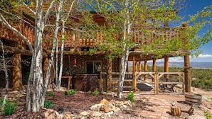 A rustic cabin with a stone foundation, wooden deck, and a covered outdoor seating area. - Secluded Cabin Retreat For The Whole Family Near Royal Gorge and Local Amenities (Cañon City)