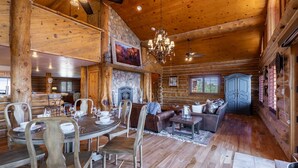 A log cabin interior with a dining area, fireplace, and a living room with a sofa and a cabinet. - Secluded Cabin Retreat For The Whole Family Near Royal Gorge and Local Amenities (Cañon City)