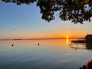 Un lago tranquilo al atardecer con un muelle que se adentra en el agua.