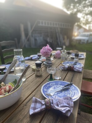 Un juego de mesa de picnic de madera con un bol de ensalada, platos, cubiertos y una botella de agua.