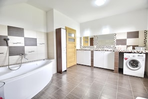 Une salle de bain moderne équipée d’une baignoire, d’une douche et d’un lave-linge.