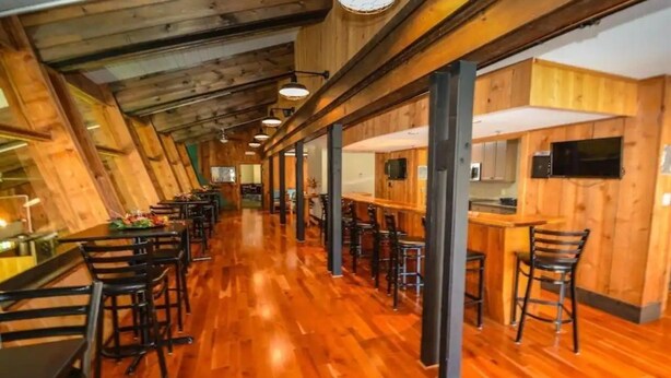 Een restaurant met houten inrichting, lange tafels en een bar.