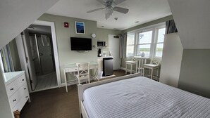 A hotel room with a bed, a desk, a chair, a TV, a microwave, and a window with a view.
