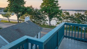 A view from a balcony overlooking a lake with boats, a bridge, and a row of houses.