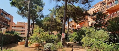 Een binnentuin met bomen, een geplaveid pad en woongebouwen met balkons.