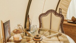 A round glass table with a wooden base, surrounded by a wooden chair with a curved backrest.