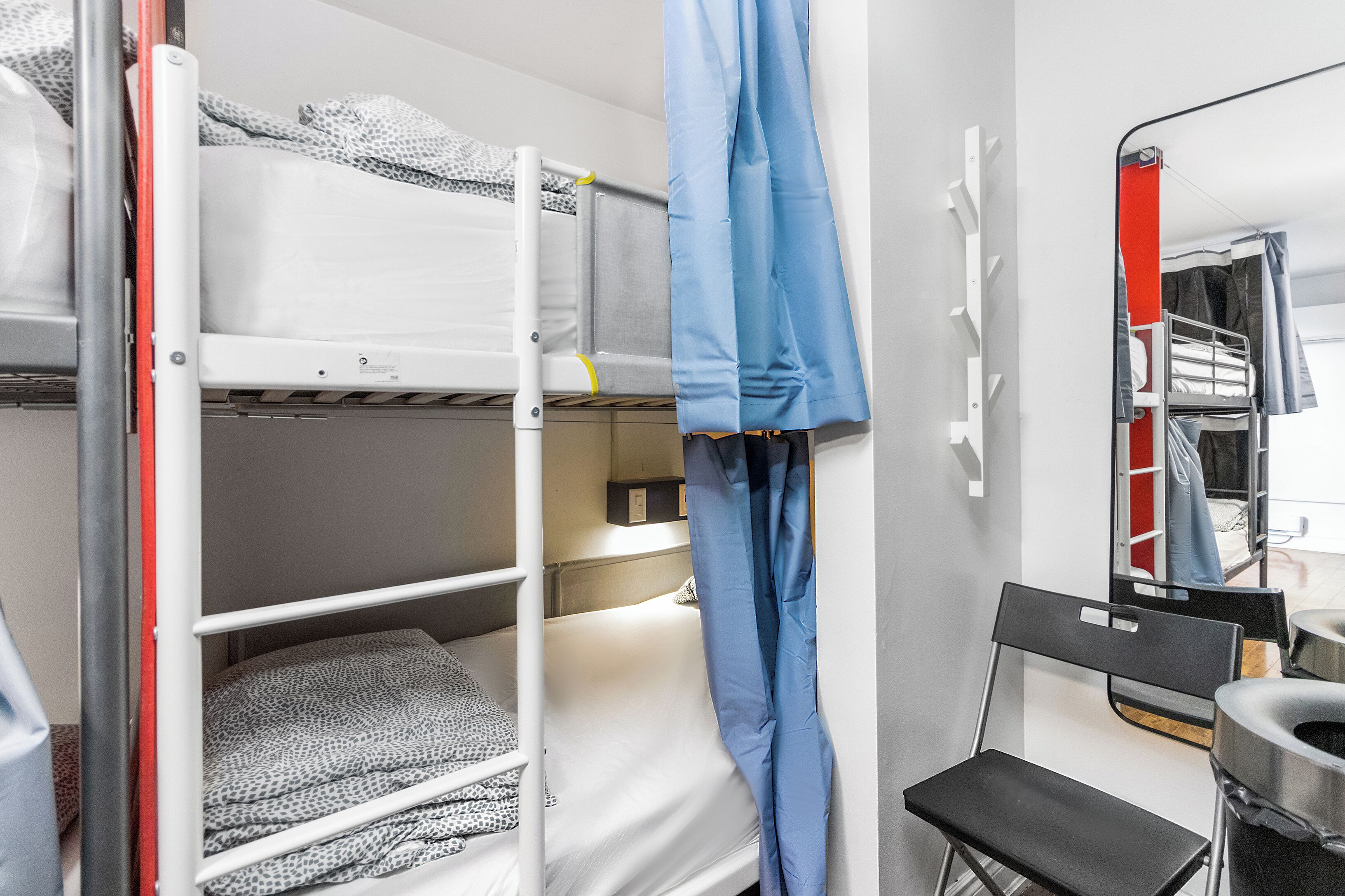 A bunk bed room with a chair and a small table.