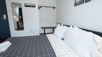 Habitación de hotel con una cama grande, un banco, un espejo y un perchero en la pared.