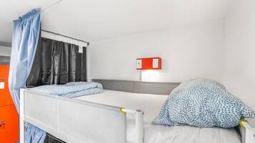 Una cama litera con colchón blanco, cabecera gris y almohada de diseño azul.