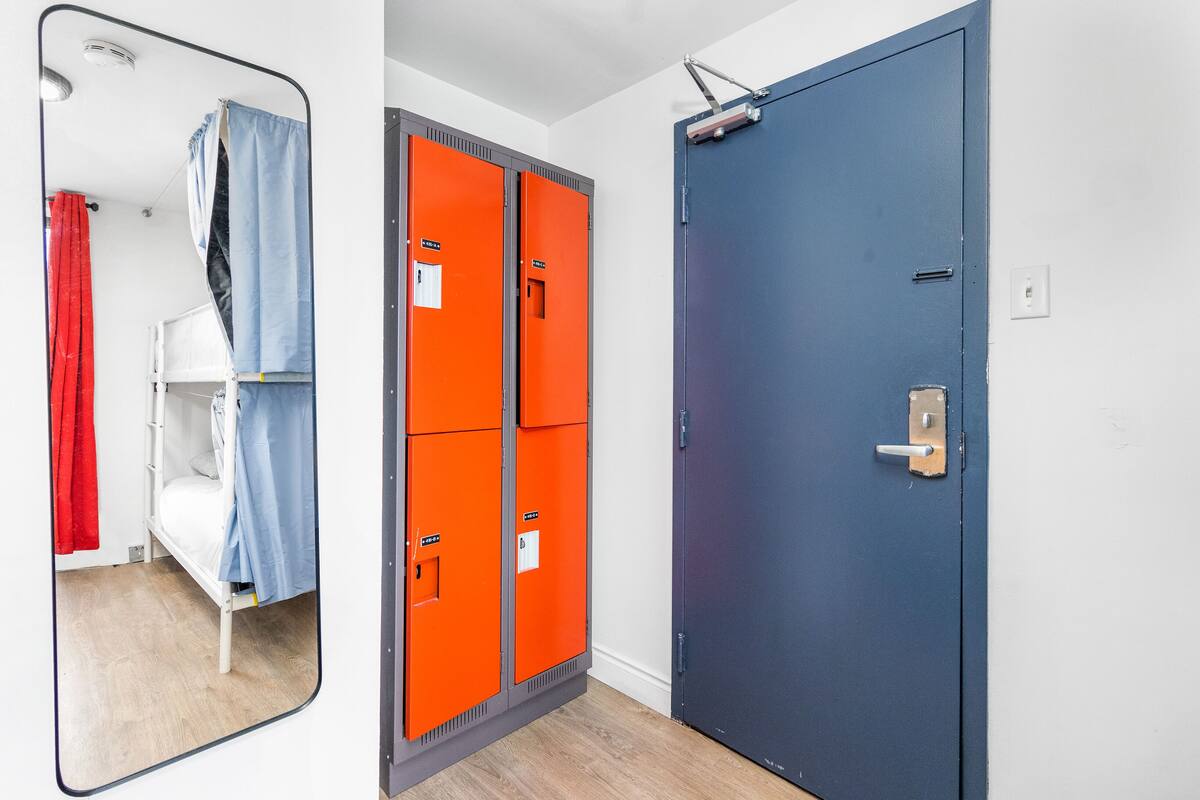 A room with a bunk bed, orange lockers, and a blue door.