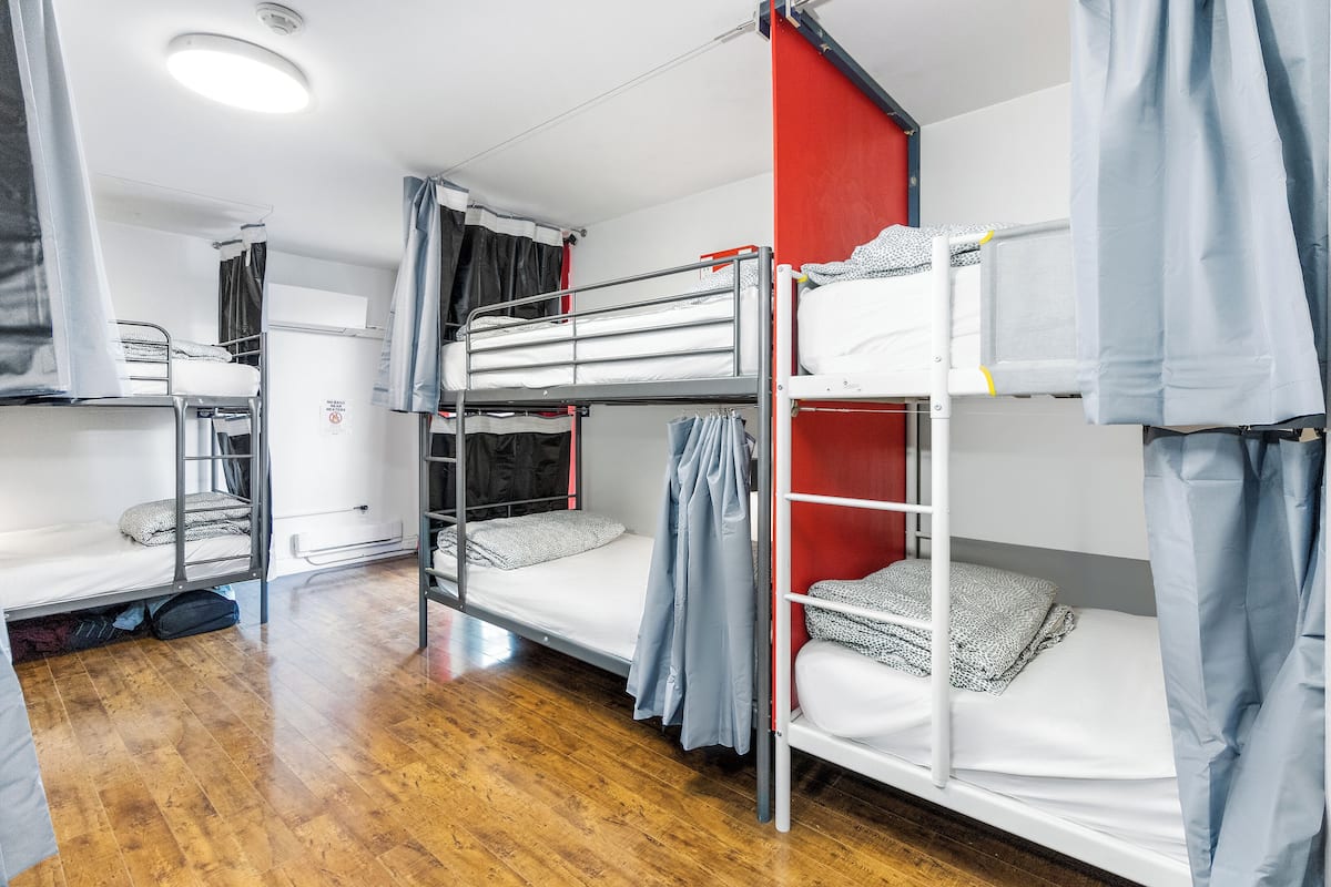 A dormitory room with bunk beds, a wardrobe, and a small kitchenette.