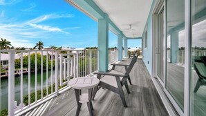 A balcony with a view of a river and palm trees, featuring a table and chairs. - P70 - Stunning 5 bed, 5 bath home with dockage and oversized private pool in Key Colony! (Key Colony Beach)