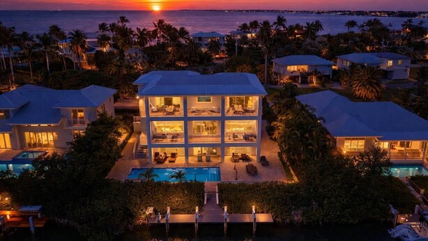 A multi-story house with a pool, surrounded by palm trees and a sunset view. - P70 - Stunning 5 bed, 5 bath home with dockage and oversized private pool in Key Colony! (Key Colony Beach)