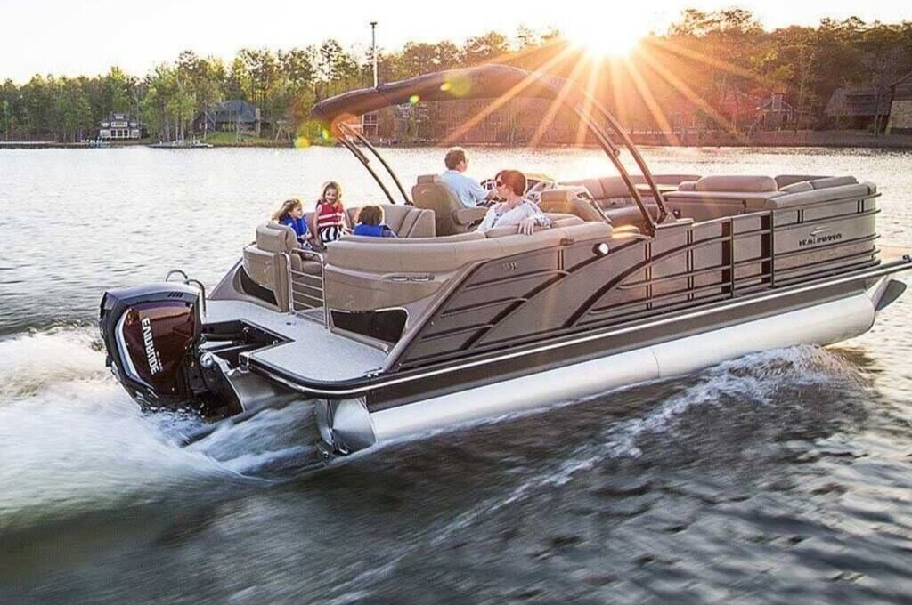Een motorboot met een hutje en zitplaatsen voor passagiers, vaart over het water met een achtergrond van bomen en een huis.