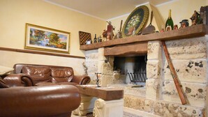 Ein traditionell eingerichtetes Wohnzimmer mit Kamin aus Stein, Ledermöbeln und einem dekorativen Kaminvorsatz.