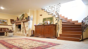 Ein geräumiges Wohnzimmer mit Kamin, einem großen Teppich und einer Treppe mit aufwendiger Geländerarbeiten.