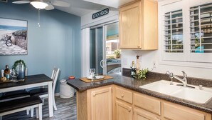A kitchen with wooden cabinets, a granite countertop, and a window with blinds.