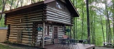 Une cabane en rondins avec une terrasse et des meubles d’extérieur.