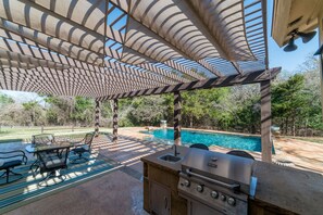 An outdoor patio with a grill, seating, and a pool. - Queen and Duke Cottage (Alvord)