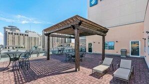 Une terrasse sur le toit avec des sièges extérieurs, une pergola et une vue sur le panorama urbain.
