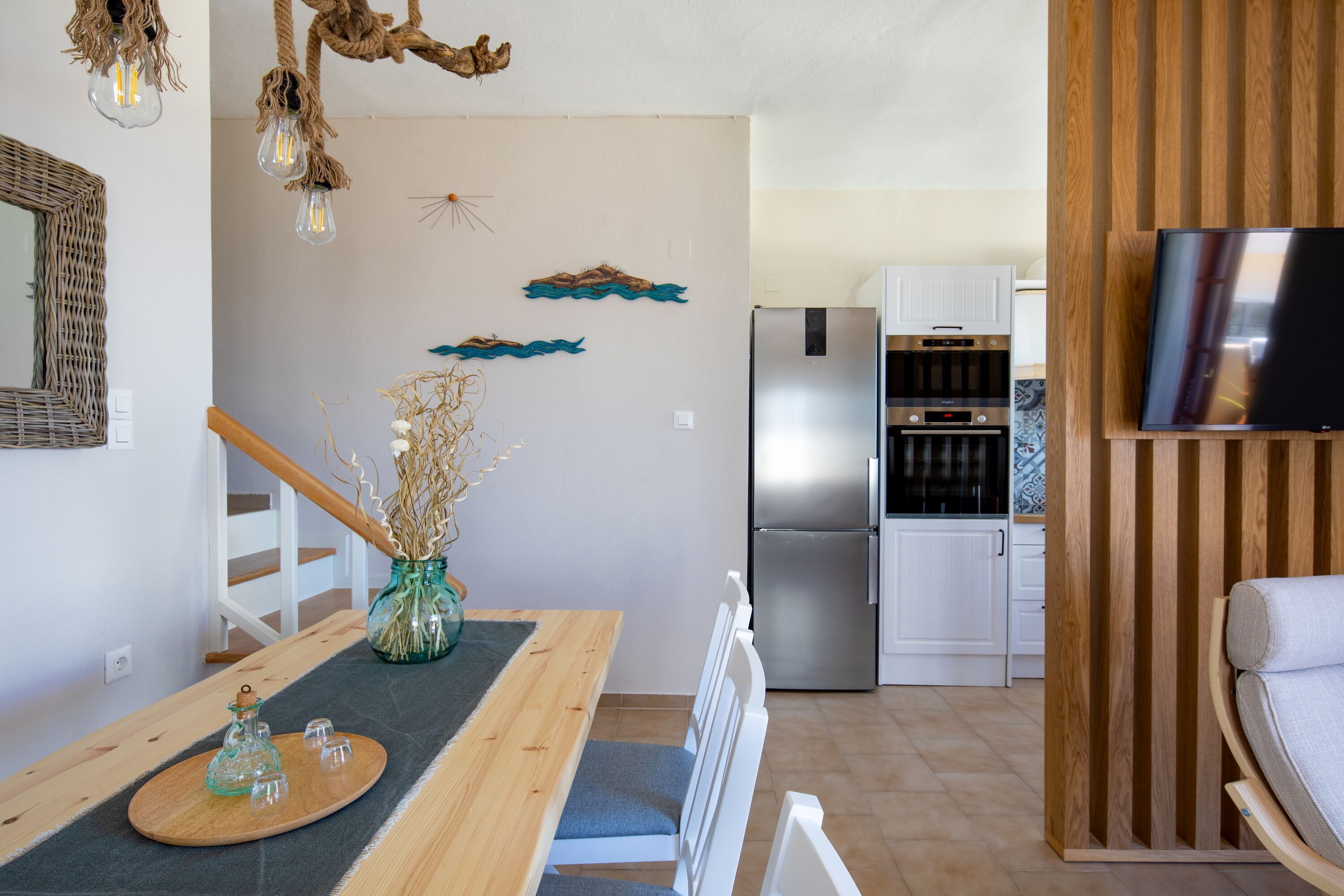 Una cocina moderna con armarios blancos, un refrigerador de acero inoxidable y un horno empotrado.